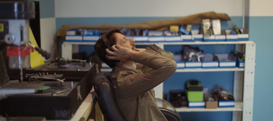 Side view of owner with eyes closed listening music through headphones at bicycle workshop