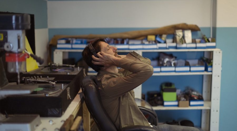 Side view of owner with eyes closed listening music through headphones at bicycle workshop