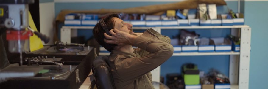 Side view of owner with eyes closed listening music through headphones at bicycle workshop