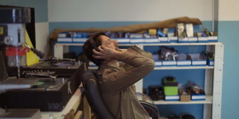 Side view of owner with eyes closed listening music through headphones at bicycle workshop